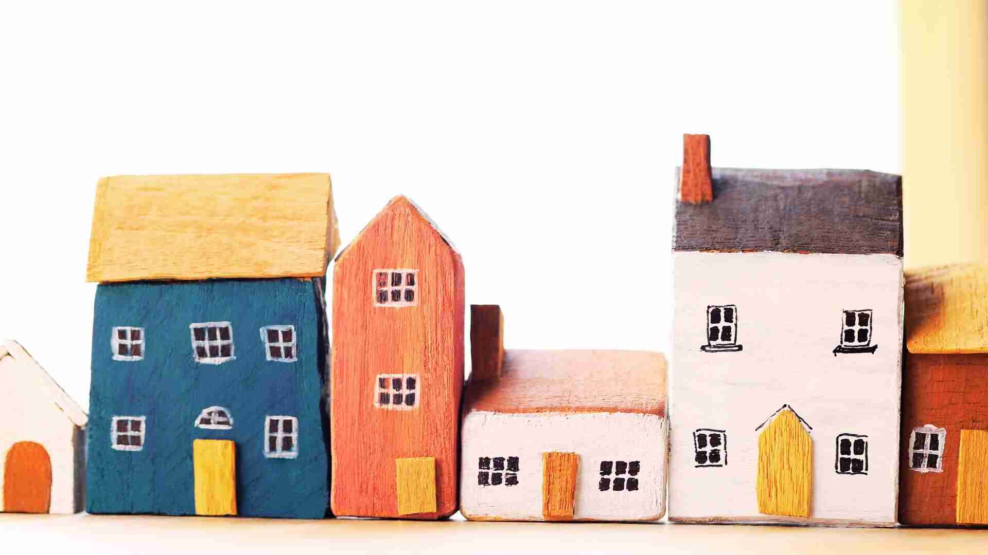 Eine Reihe von bunten Holzhausmodellen in verschiedenen Formen und Farben auf einem Tisch.