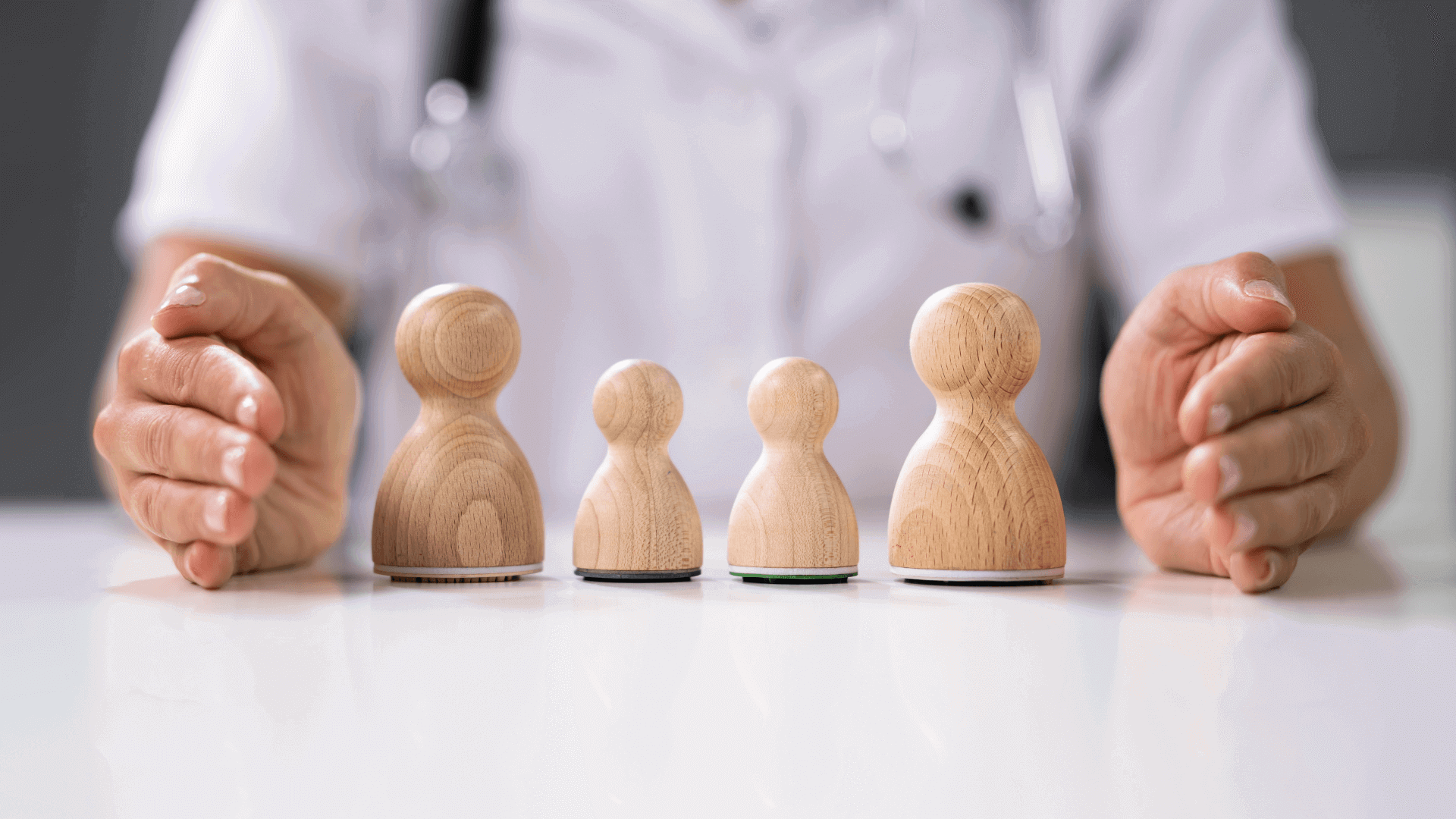 Vier Holzfiguren in unterschiedlichen Größen auf einem Tisch, von einer Person gehalten.